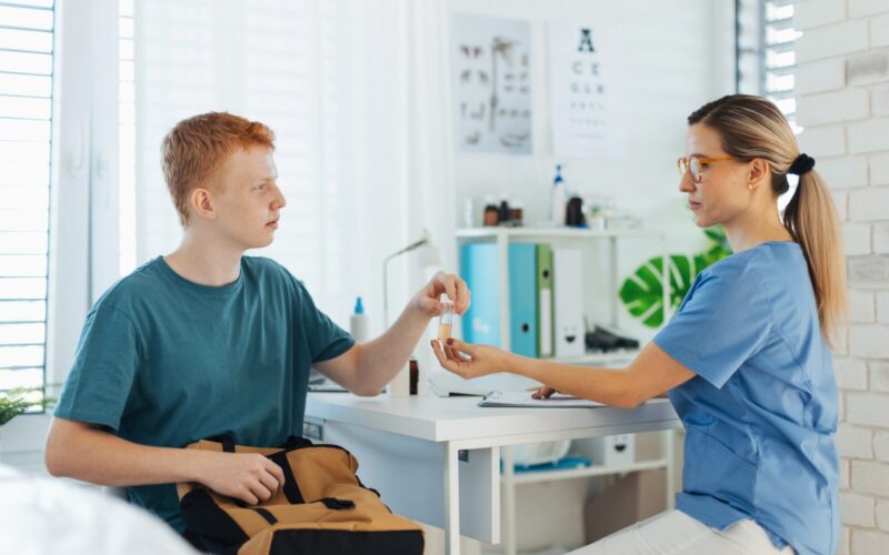 Diabetologist doctor doing regular urine test for teenage diabetic patient in diabetes clinic