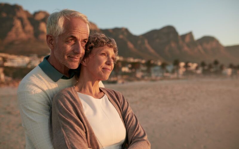 Elderly couple standing together and embracing on the beach